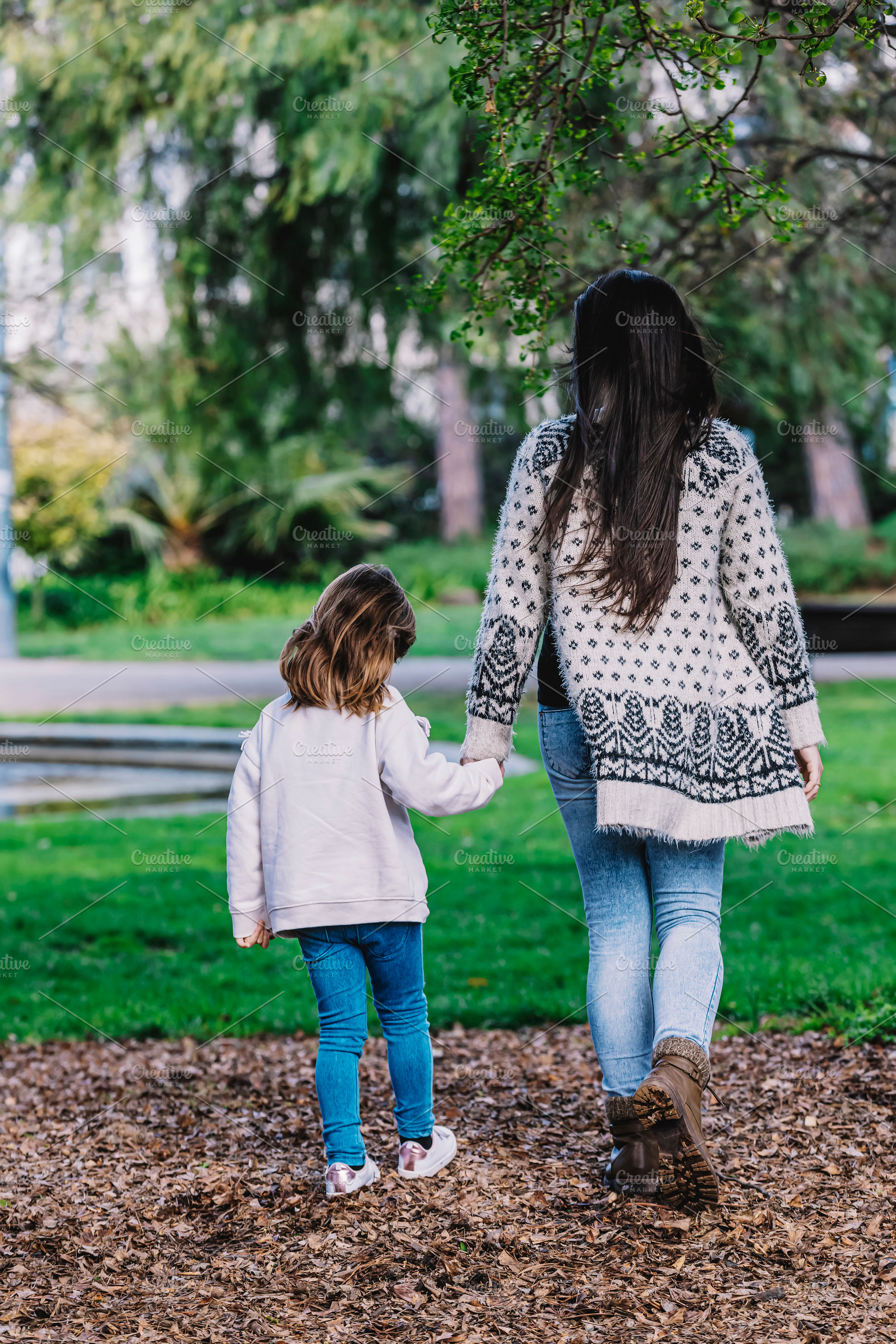 Rear view of a mother with her baby. Mom and daughter in an autumn park, a Person Photo by 2Design