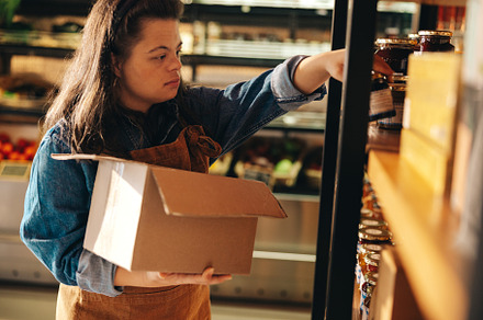 Supermarket employee with Down syndrome restocking food products, a Person Photo by Jacob Lund