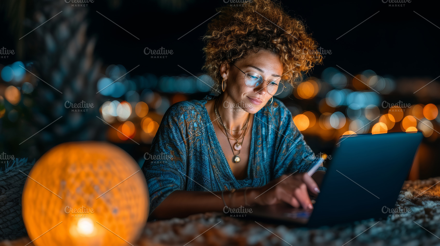 Woman working on laptop outdoors with warm lantern lighting at nighttime, a Business Photo by AS photostudio