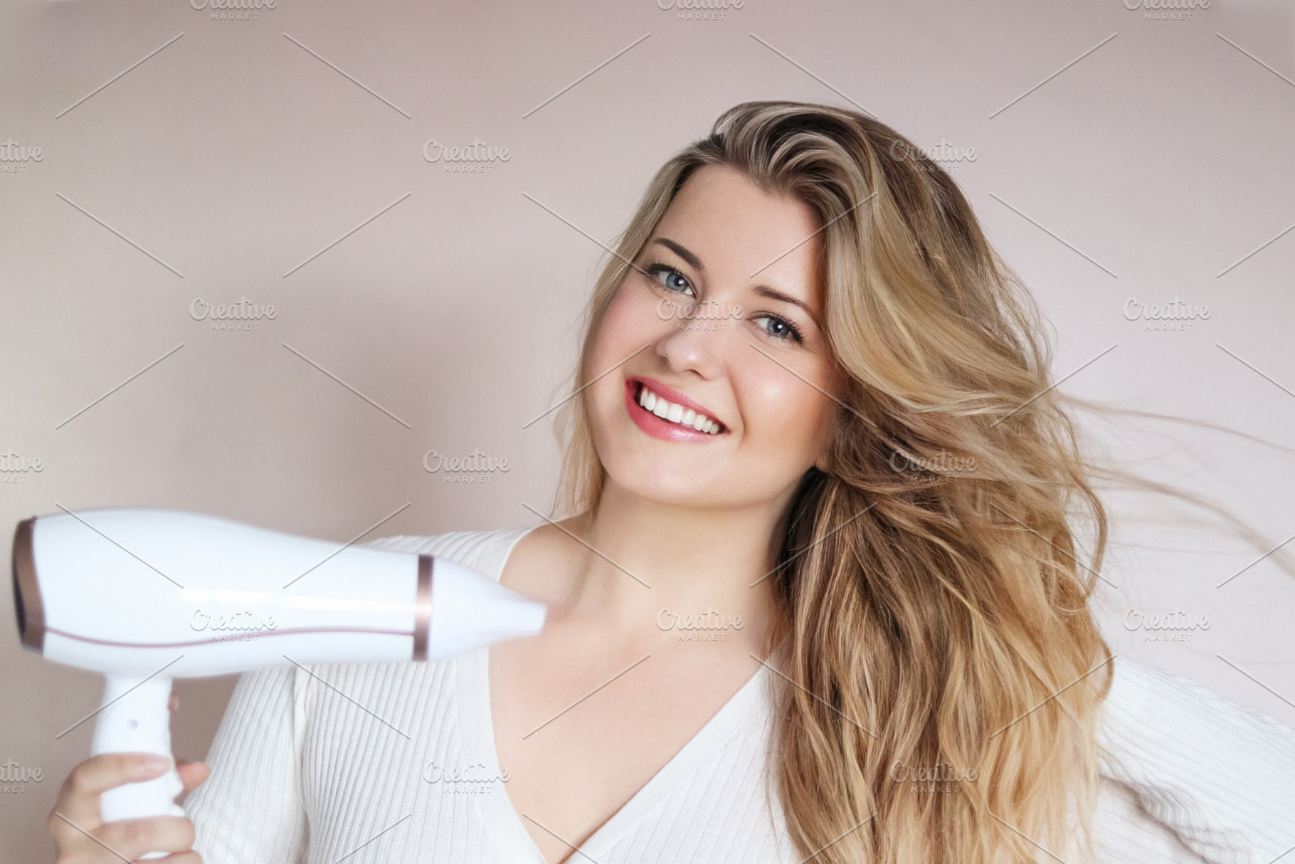 Happy young woman blow drying her long blonde hair for beauty, s, a Person Photo by Studio ANNA