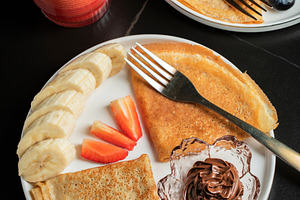 A plate of crepes filled with chocolate spread and topped with banana slices an, a Food & Drink Photo by Budarinphoto
