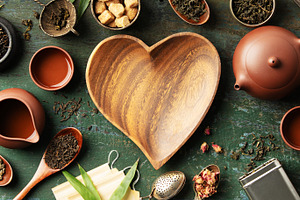 Heart-Shaped Bowl with Teaware and Tea Leaves on Rustic Backgrou