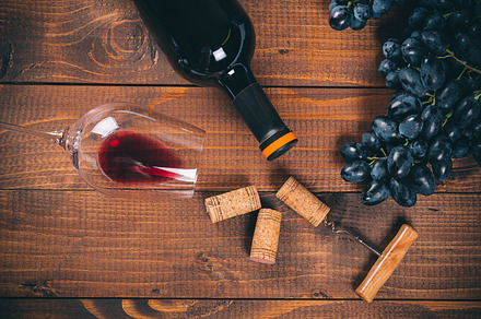 Bottle and glass of red wine grape corkscrew and cork on wooden background