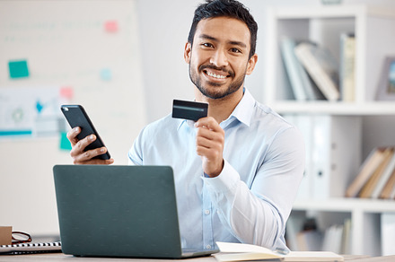 Credit card, phone payment and businessman shopping on the internet, banking on mobile app and working in finance in work office. Portrait of smile Asian employee using online retail service on web, a Photo by Peopleimages.com