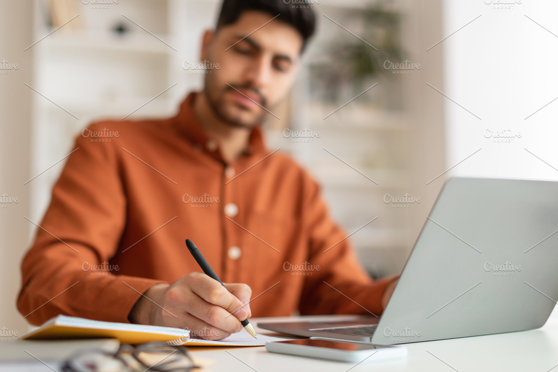 Portrait of focused Arab man using pc and writing, a Photo by Prostock-Studio
