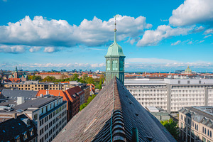 Trinitatis Church spire over Copenhagen rooftops, a Photo by Nito