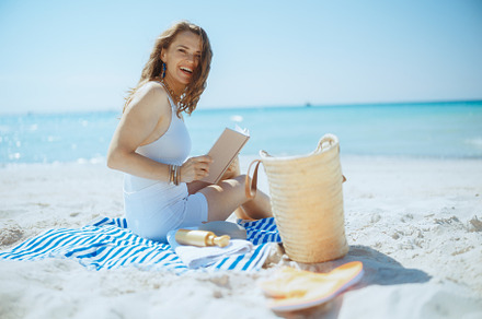 smiling stylish woman on ocean shore with straw bag, a Person Photo by Alliance Images