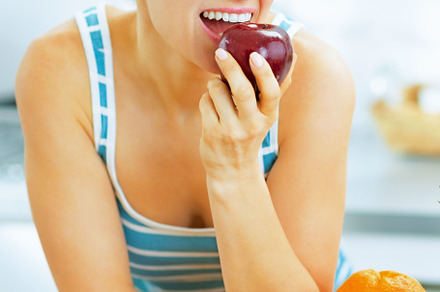 Young woman eating apple in kitchen, a Person Photo by Alliance Images