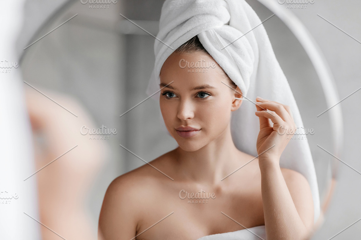 Daily hygiene routine. Young woman cleaning ears using cotton swab while doing, a Photo by Prostock-Studio (Photo 1 of 3)