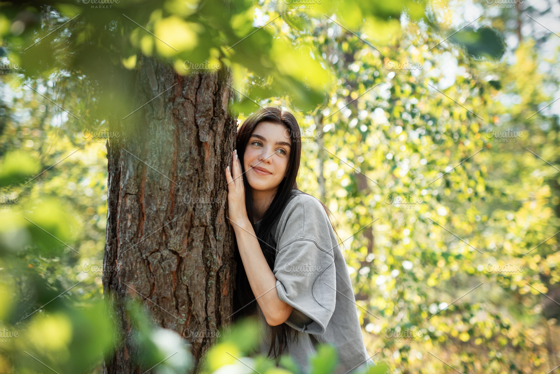 Young woman enjoying a peaceful moment by a tree in a lush green, a Person Photo by Olena Rudo