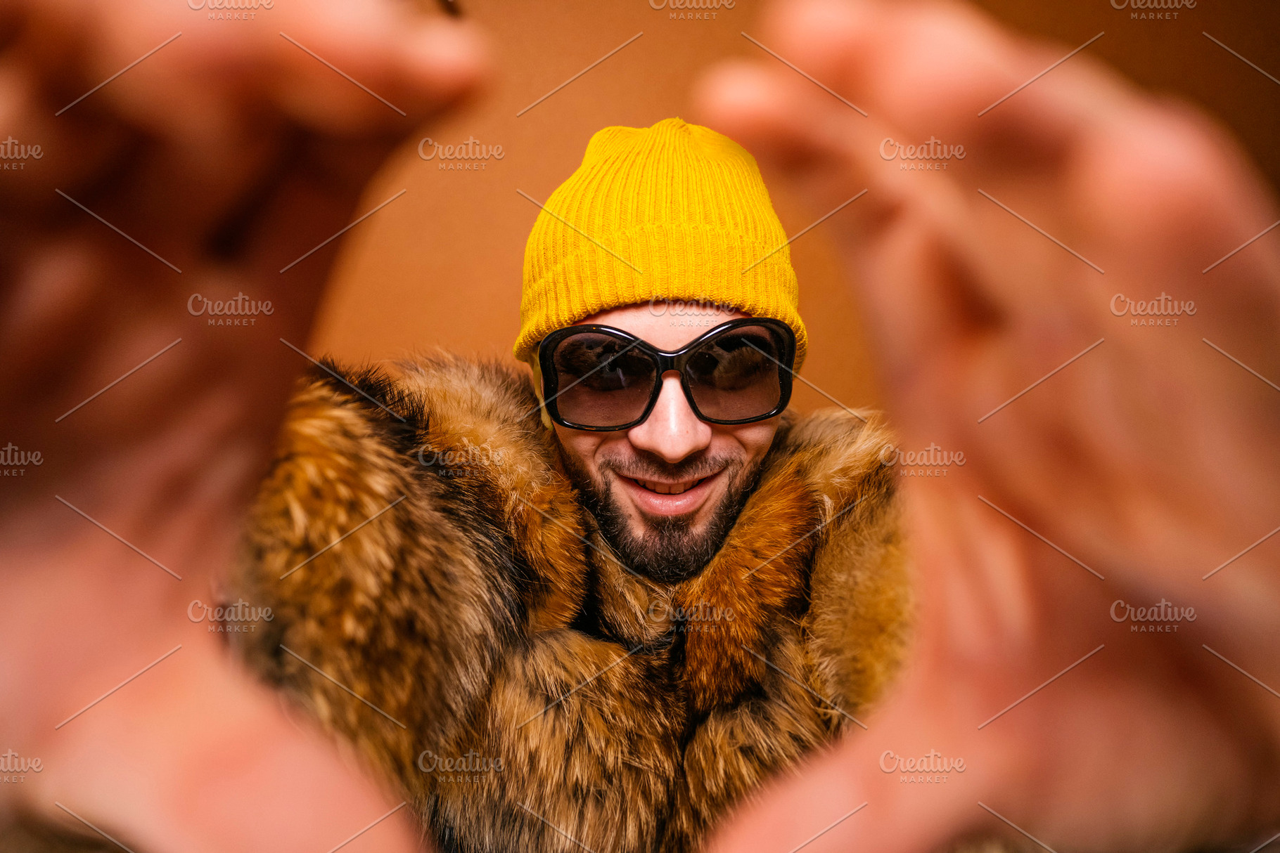 Fashionable man smiling through heart-shaped hands showing confidence, a Photo by karrastock