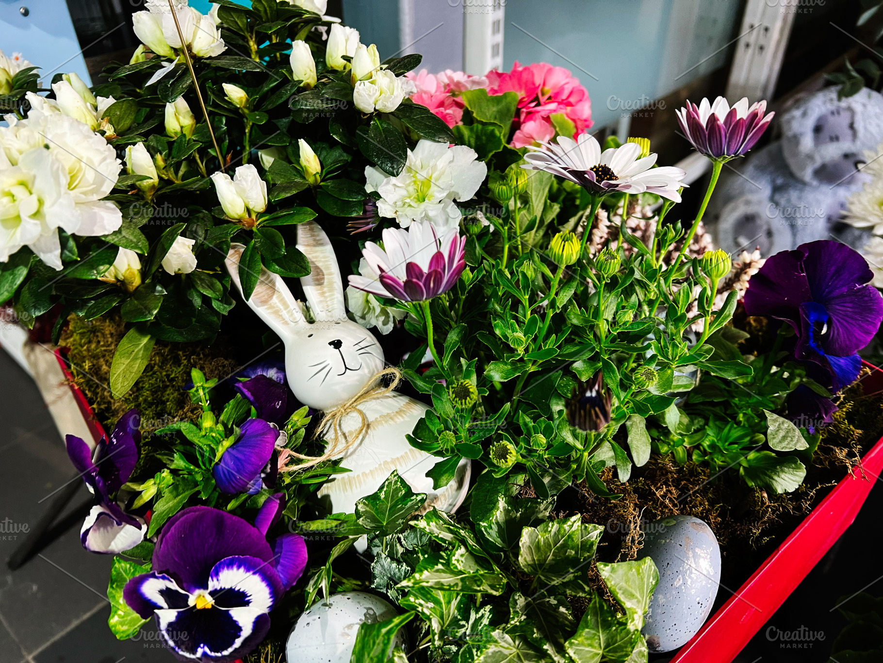 Decorative rabbit among colorful spring flowers and green foliage in a garden s, a Photo by AS photostudio