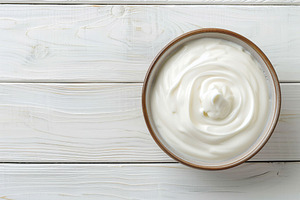 Bowl with white yogurt on wooden table, a Food & Drink Photo by AlyaAnd