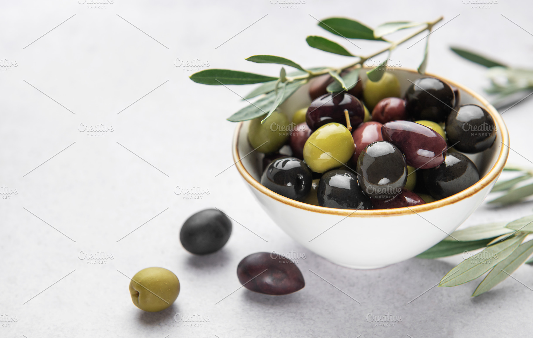 Fresh olives with olive branch in white bowl on marble table, a Food & Drink Photo by Olena Rudo
