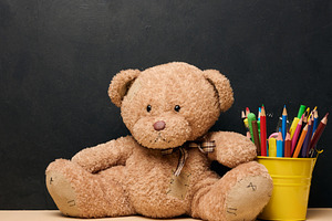 A brown teddy bear sits next to a yellow bucket filled with colo, a School & Education Photo by ndanko