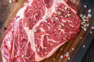 Raw ribeye steak on a wooden board w, a Food & Drink Photo by Alexander Prokopenko