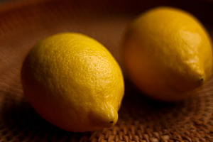 Fresh yellow lemons showing textured skin and bright color on a woven wicker ba, a Photo by Studio ANNA