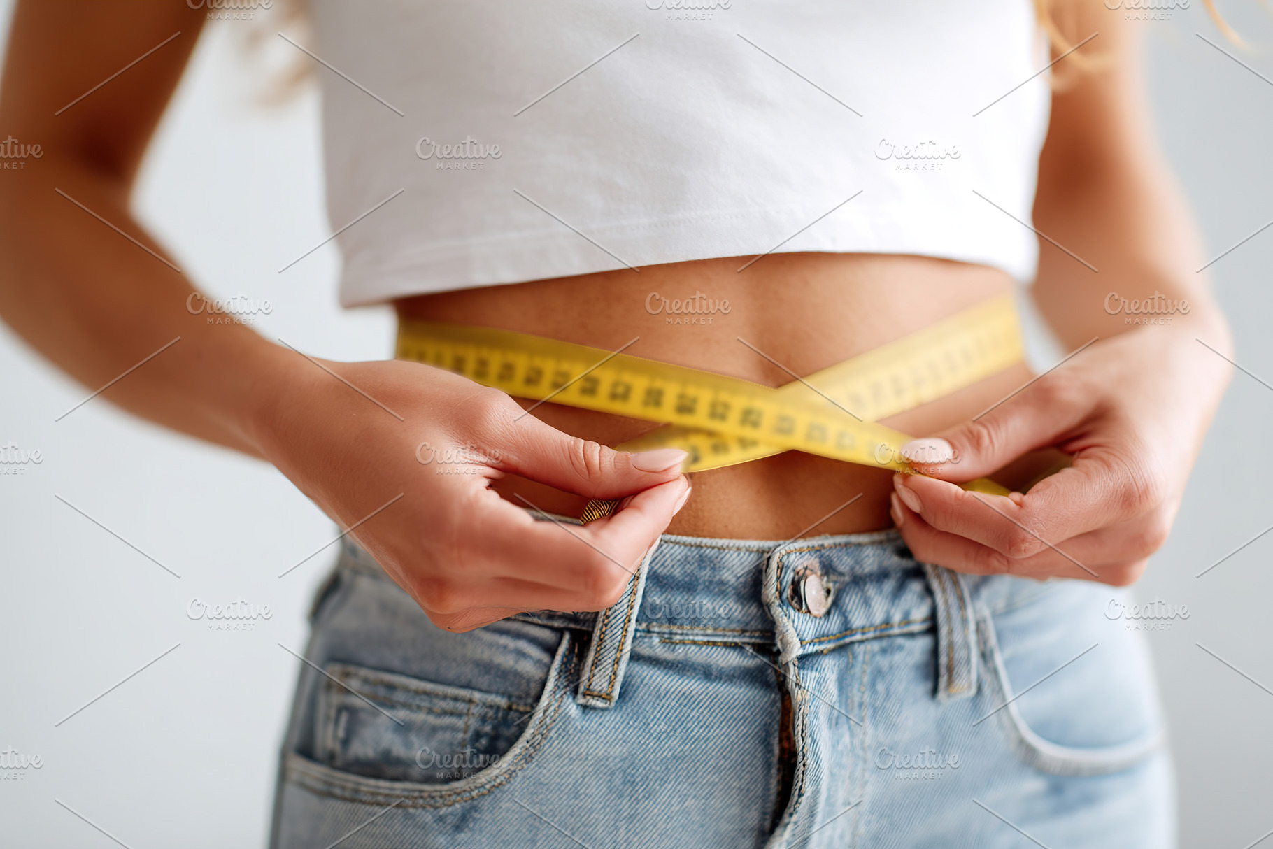 Woman measures her waist with a measuring tape while wearing casual clothing in, a Photo by AlyaAnd