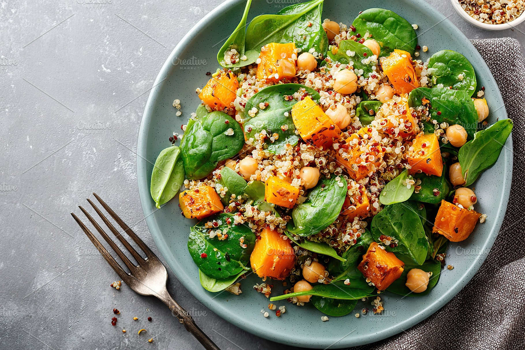 Healthy quinoa salad with butternut squash and spinach served on a plate, a Photo by AlyaAnd