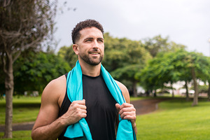 Smiling athletic man resting after fitness workout in green park