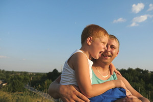 Close up of smiling boy sitting at featuring adult, background, and boy
