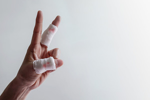 Hand with bandaged fingers raised against plain background. Conc, a Photo by salmon.black