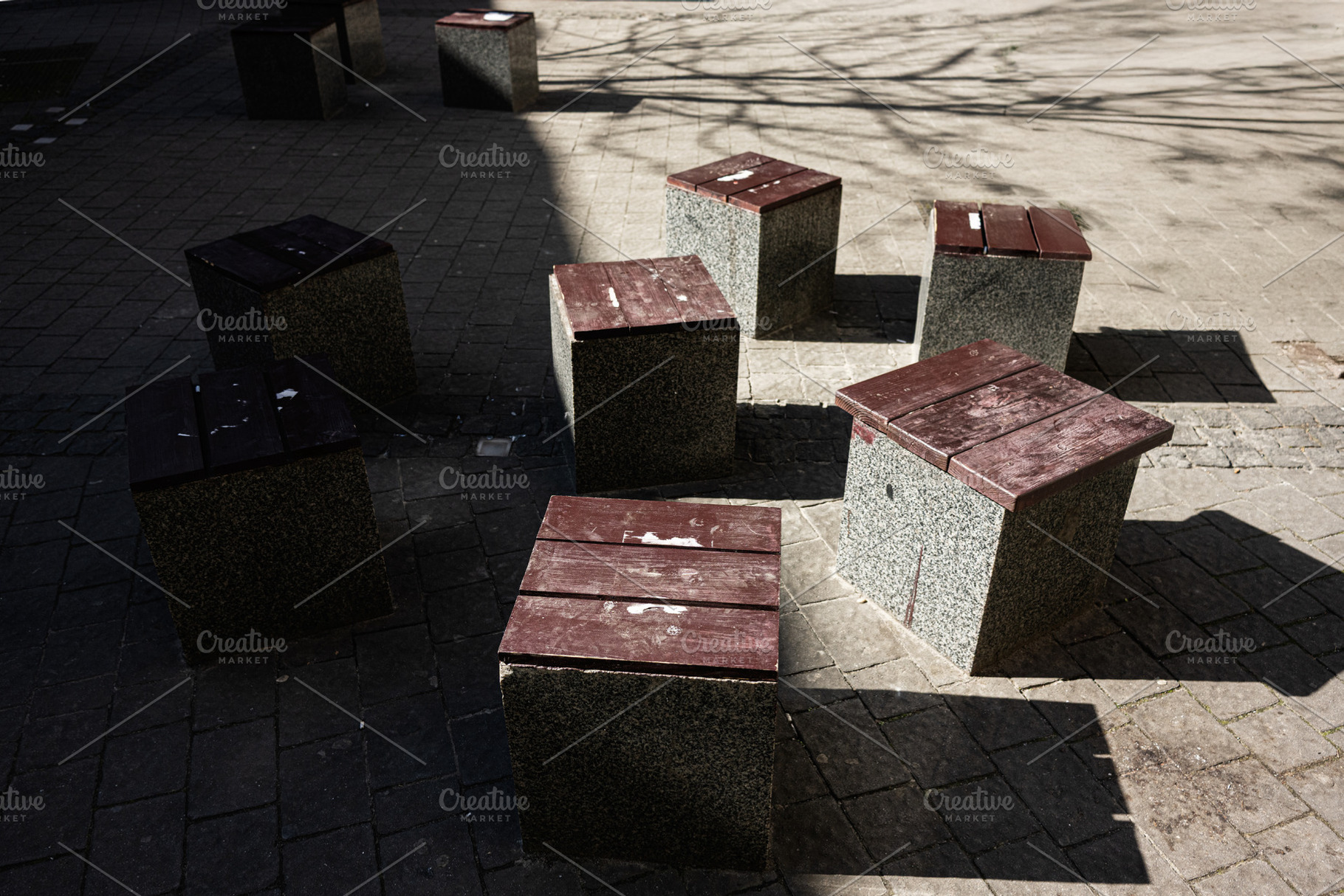 Concrete stools in outdoor arrangement with wooden seating under natural sunlig, a Photo by AS photostudio
