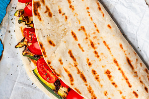 Piadina with grilled zucchini and tomatoes on burnt baking paper, a Food & Drink Photo by Antonio Gravante Market