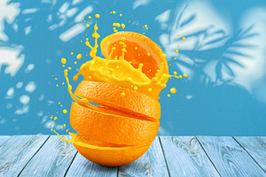 Sliced orange fruit splashing about orange juice on blue table a, a Food & Drink Photo by Volff