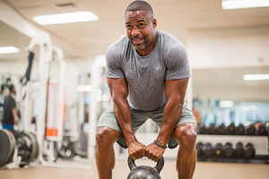 Man lifting kettlebell in gym, a Sports & Recreation Photo by AlyaAnd