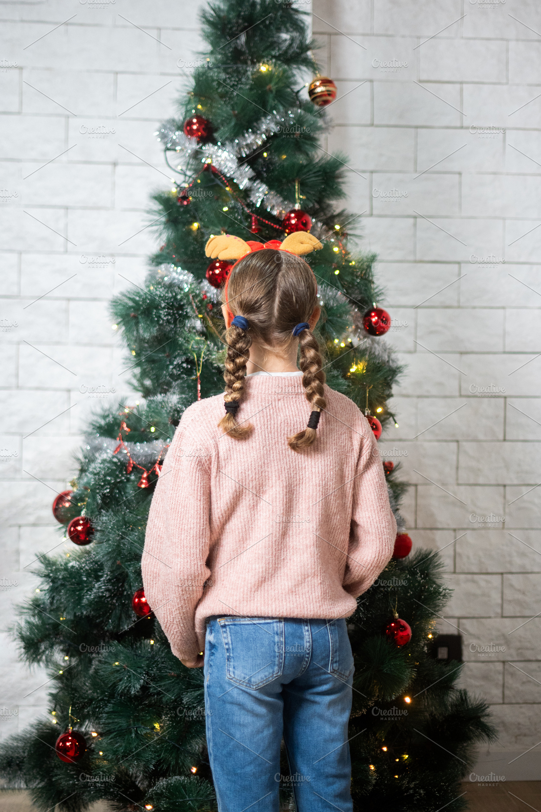 Young girl looking at decorated Christmas tree from behind, a Holiday Photo by etorres69