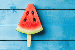 Refreshing watermelon slice shaped like an ice pop on blue wooden surface, a Food & Drink Photo by AlyaAnd