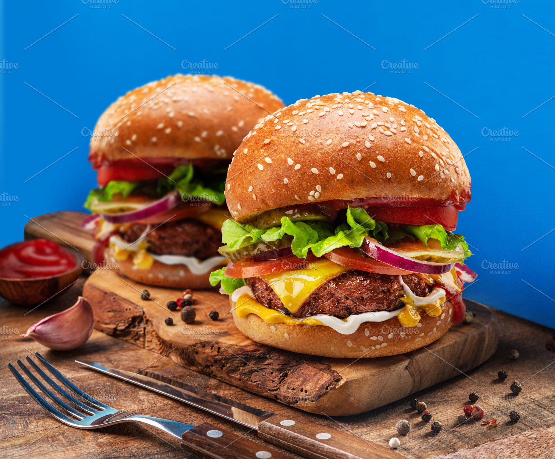 Tasty cheeseburgers on wooden tray close-up. Blue background., a Food & Drink Photo by Volff