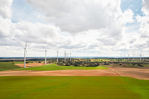 Vast solar and wind energy farm under bright cloudy sky, a Photo by andreonegin market