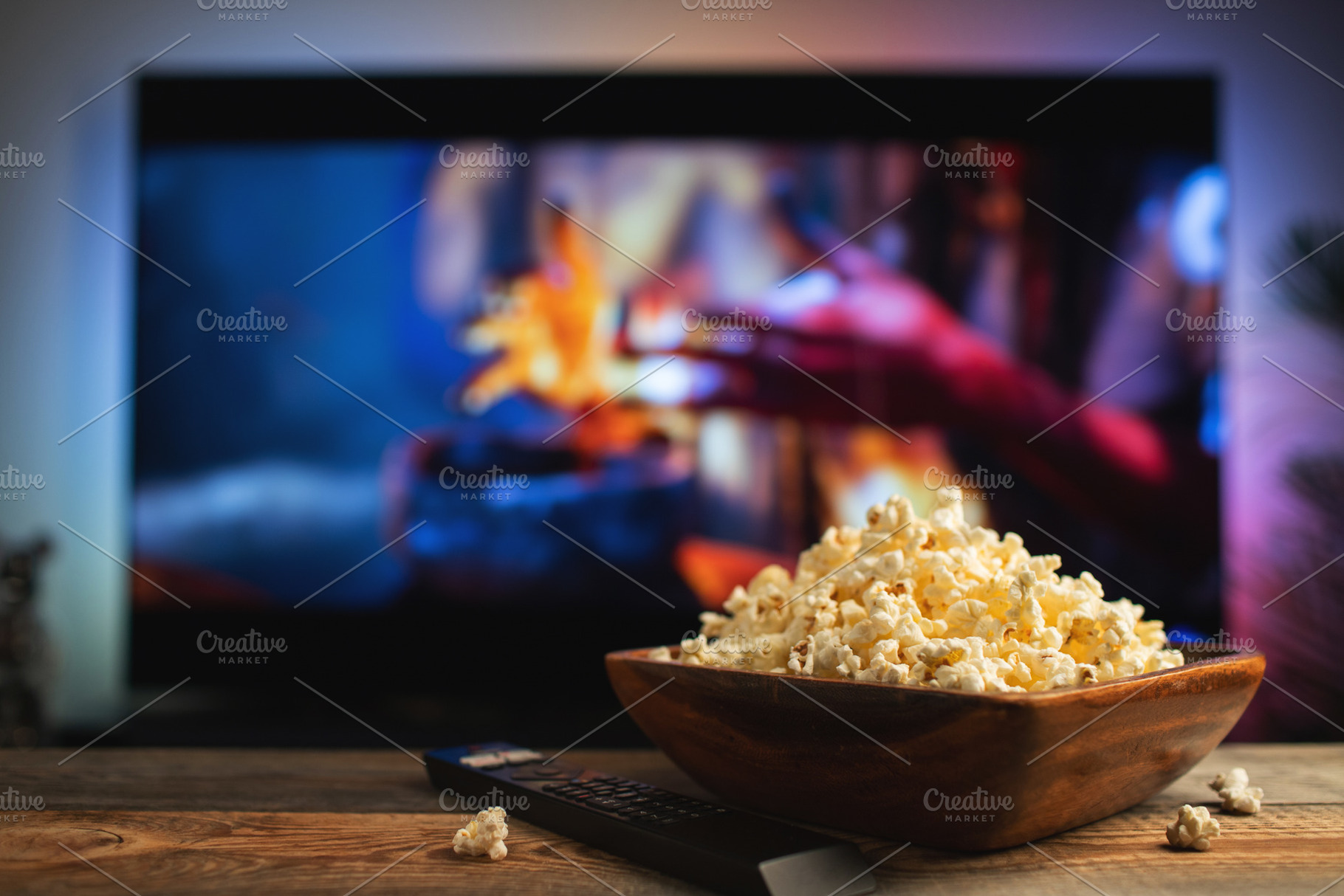 A wooden bowl of popcorn and remote control in the background the TV works, a Food & Drink Photo by Budarinphoto