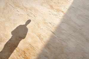 Long human shadow cast on a textured surface during bright daylight hours, a Photo by AlyaAnd