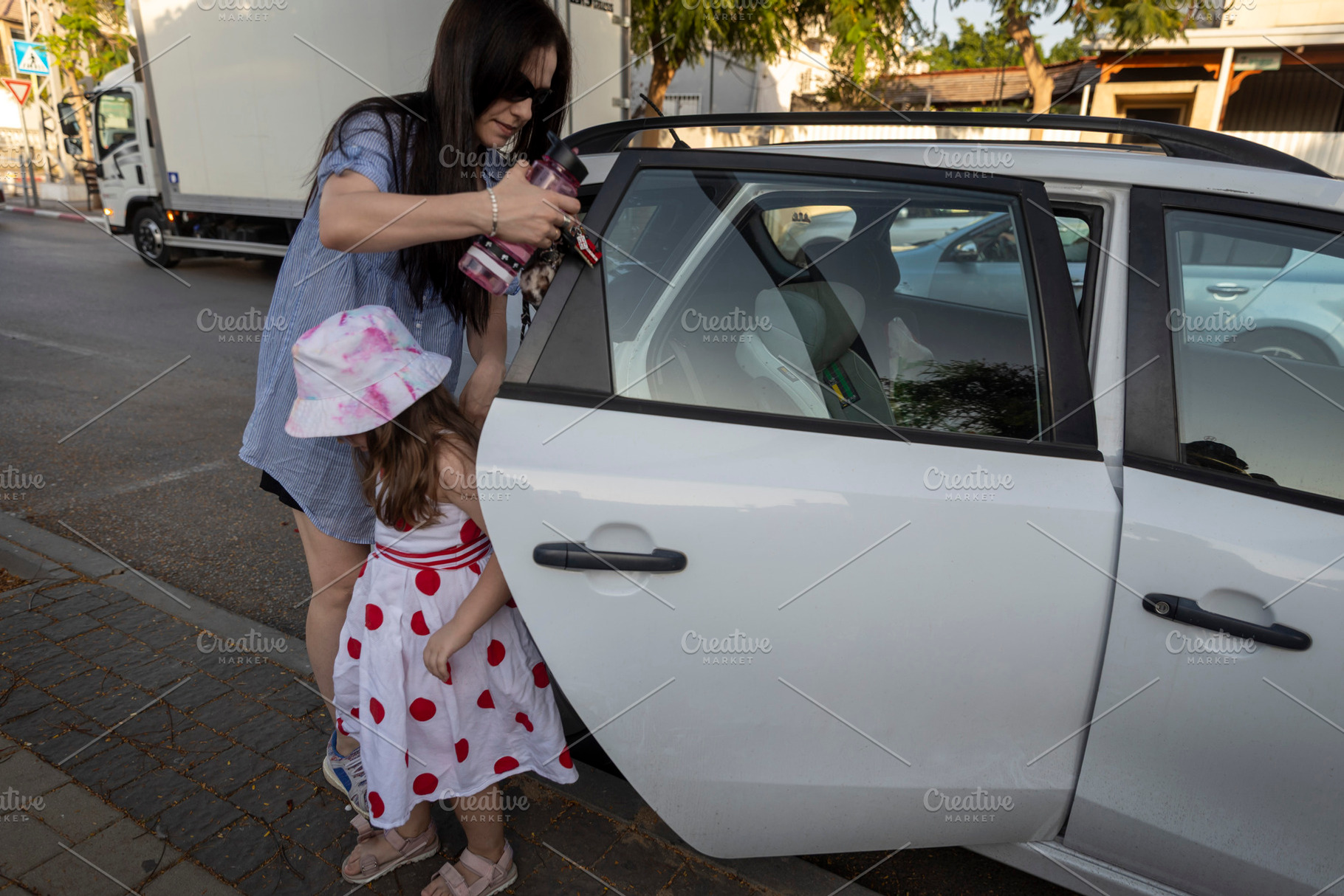 Mother preparing to put a bottle or sunscreen through the open b, a Person Photo by Imaginarium