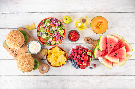 Tasty summer barbecue table with hamburgers, salads, fruits and