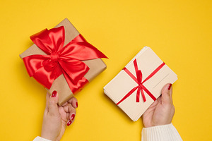A woman's hands, one holding a gift box wrapped in craft paper w, a Holiday Photo by ndanko
