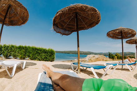 Point of view of a tourist on deck chairs with straw parasols near the river, a Holiday Photo by rubenchase