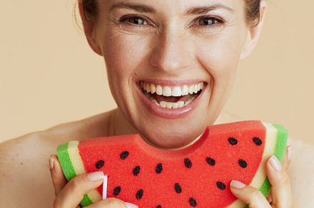 Portrait of happy modern female with watermelon shower sponge, a Beauty & Fashion Photo by Alliance Images