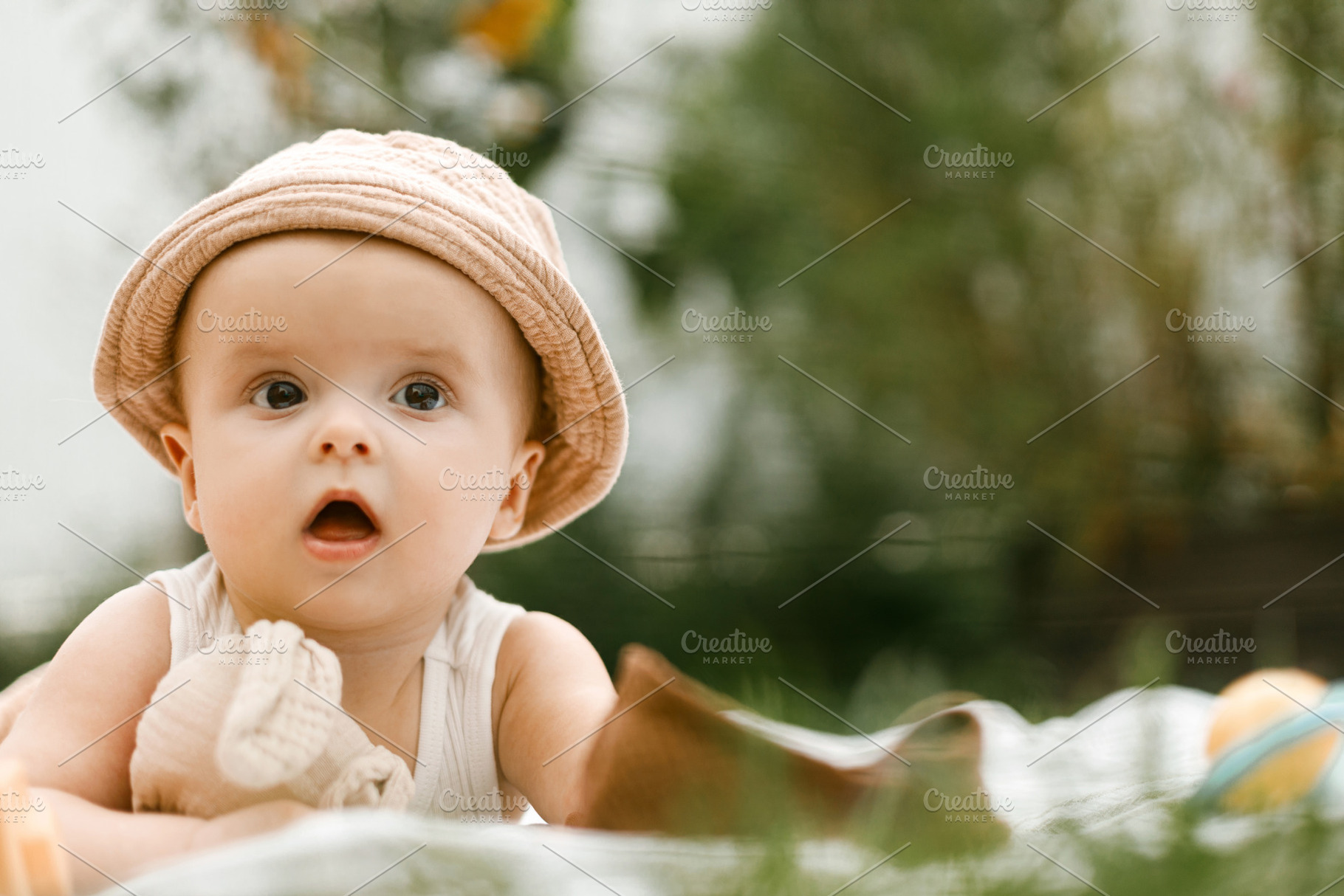 Beautiful happy baby in hat lying on blanket and playing with to, a Person Photo by Sonjachni