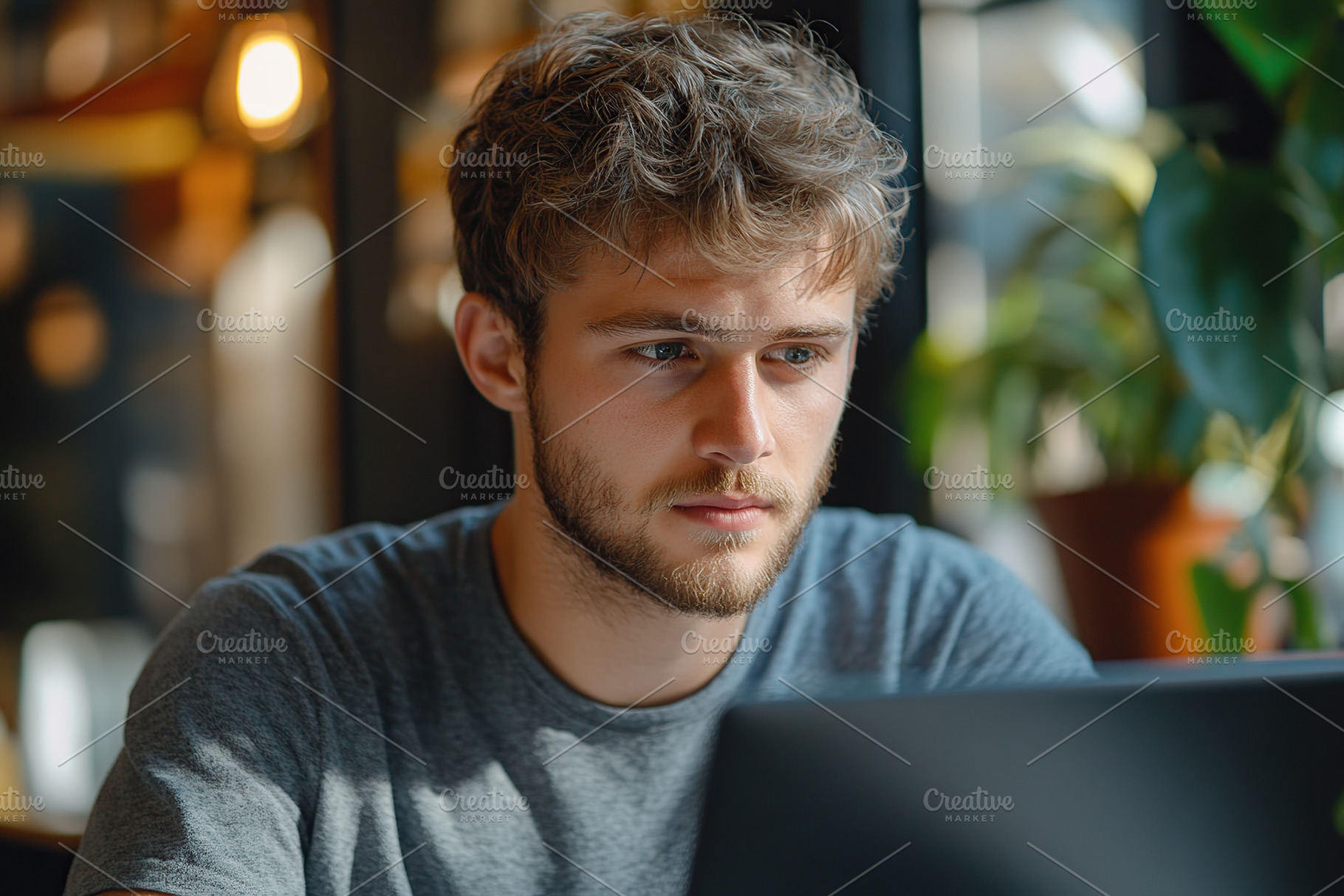 Young man focused on laptop in a modern cafe setting, a Person Photo by AlyaAnd
