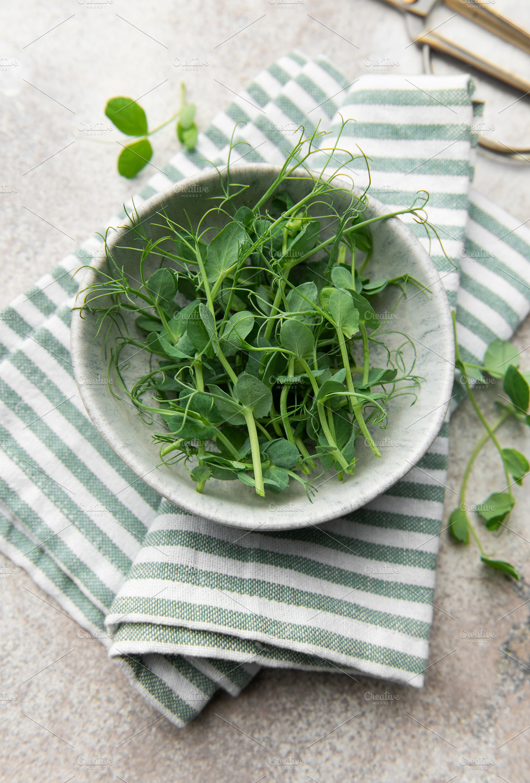 Fresh green pea shoots in bowl with striped cloth, a Food & Drink Photo by Olena Rudo