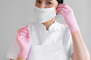 Female dermatologist wearing surgical mask and pink gloves in clinic, a Person Photo by andreonegin market