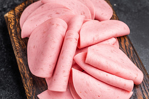 Overhead view of cold cuts (mortadella) on a small wooden board., a Food & Drink Photo by composter-box@mail.ru