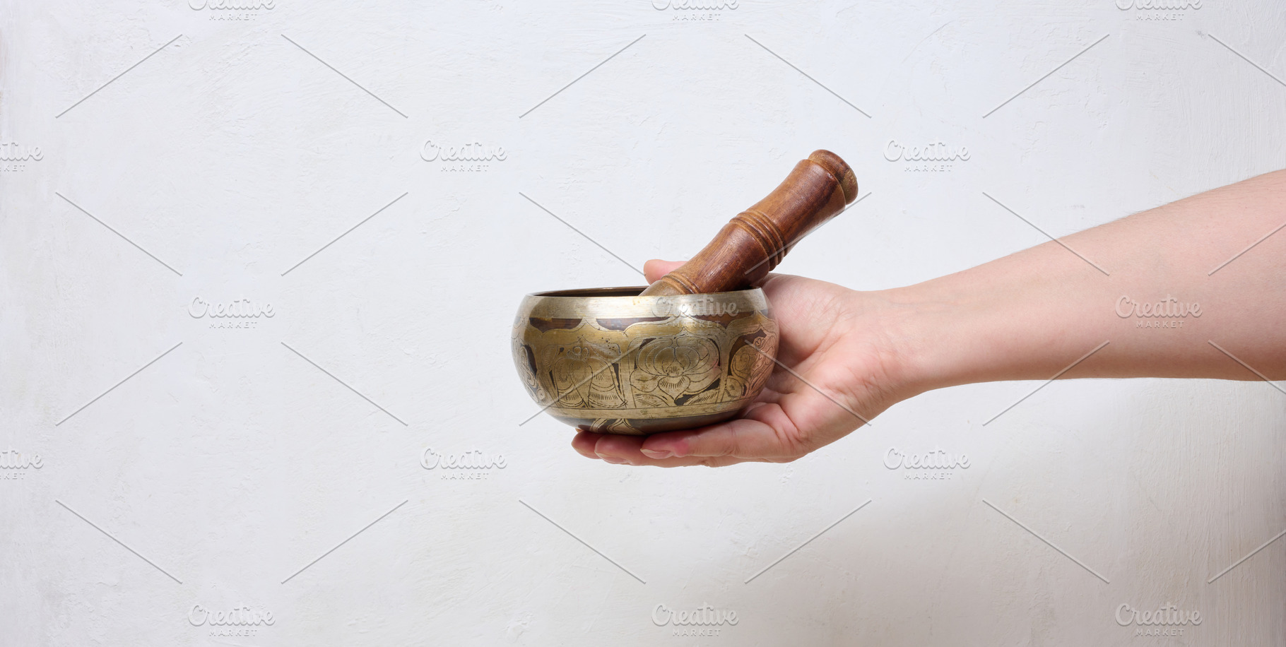A person holding a metal singing bowl with a wooden stick in the, a Health & Medical Photo by ndanko