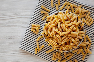 Uncooked Organic Dry Fusilli Pasta in a Bowl, top view., a Food & Drink Photo by LiudmylaChuhunova