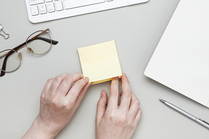 Female hand making reminder note on adhesive memo paper placed on tidy desk wit, a Photo by matucha
