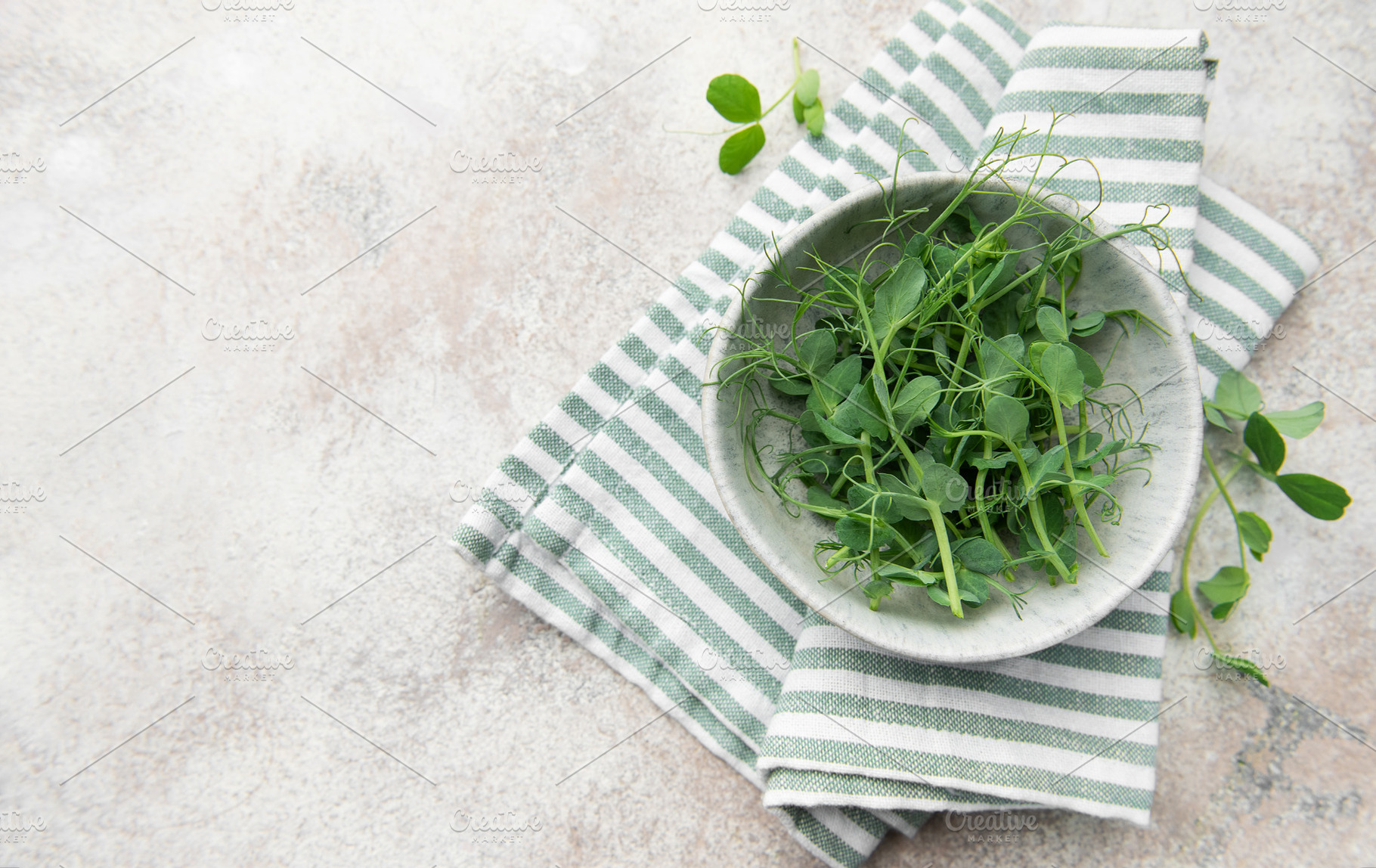 Fresh green pea shoots in bowl on towel, a Food & Drink Photo by Olena Rudo